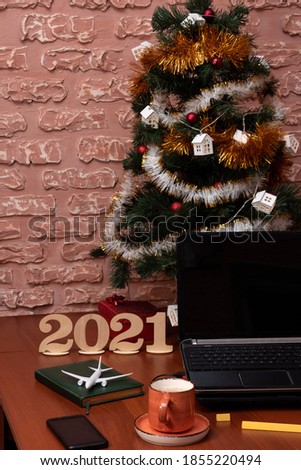 Laptop, phone, diary, airplane with a Christmas tree on the desktop of a freelancer. New year mood.