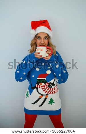 Woman wearing sweater and Christmas hat, having a cup of coffee in hand.