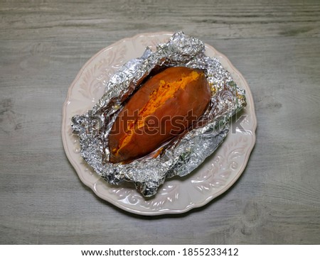 An oven baked sweet potato wrapped in foil paper. 