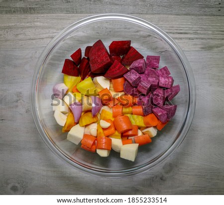 Colorful root vegetables cut up into pieces in a glass bowl.