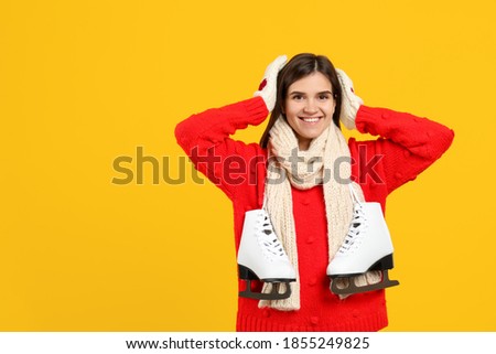 Happy woman with ice skates on yellow background. Space for text