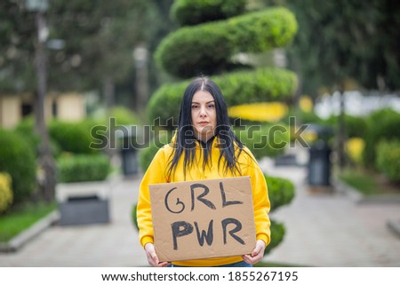 girl in yellow hoodie  with banner GRL PWR