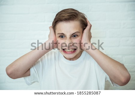 Upset teen boy closing ears. Portrait of angry guy tired of scandals or gossips. Negative emotion concept Royalty-Free Stock Photo #1855285087