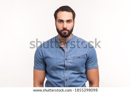 Portrait of attentive self confident bearded man looking at camera with serious expression, unsmiling determined business man. Indoor studio shot isolated on white background Royalty-Free Stock Photo #1855298098