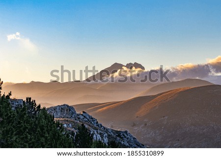 Mountain landscape at sunset with foggy clouds and golden light. Peaceful background and relax landscape. Banner and wallpaper images, backdrop and background with mountain peaceful light