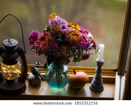 autumn windowsill.bouquet of autumn flowers,pumpkin,,lantern against beautiful autumn view