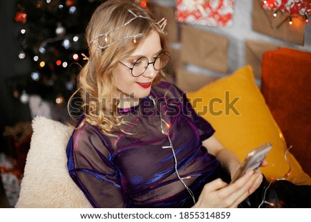 funny young Christmas girl taking selfie photo with mobile phone near Christmas tree 2021