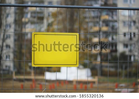 yellow sign on the fence at the construction site for the inscription