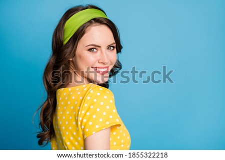 Photo portrait of woman looking behind shoulder smiling near blank space isolated on pastel light blue colored background