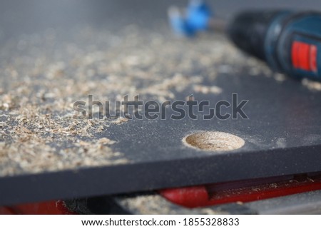 Close-up of hole on wooden board. Electrical instrument for drill. Sawdust on surface. Fixing furniture. Renovation in apartment and construction site concept