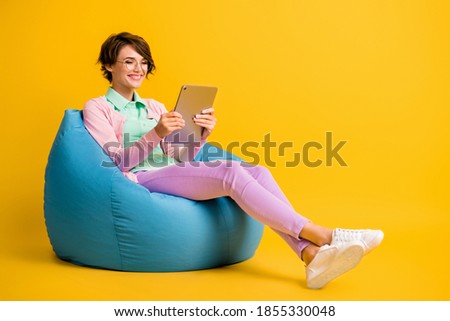 Full length body size photo female student glasses using tablet reading article in internet isolated on vibrant yellow color background
