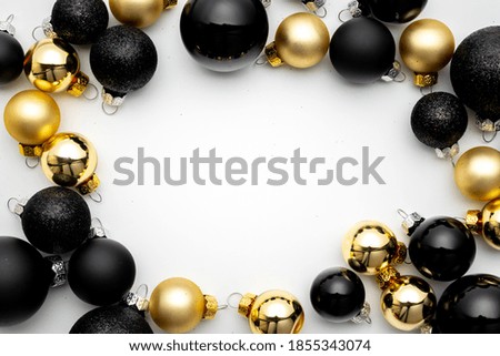 Christmas decoration golden background. Golden New Year balls, black baubles in xmas composition on white background for greeting card. Xmas backdrop with space for text.