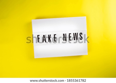 Fake News text on lightbox on yellow background isolated. vintage billboard Top view, flat lay. Information noise, political propaganda, misinformation, non-confidential sources of information concept