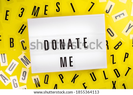 Donate Me text on lightbox on scattered letters background of plastic alphabet. call for charity donations, compassion, philanthropy, Personal assistance to disadvantaged people concept
