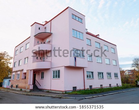 Pink round corner house building at intersection of streets. Blue sky in background