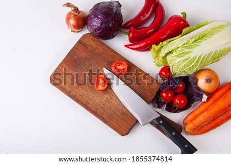Picture of a many vegetables, a clean knife and a wooden cutting board.