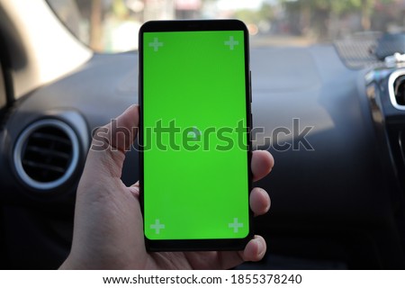 Close up image of smart phone on car mock up, riding a car with smartphone map navigation concept, blank phone green screen template