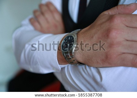 Close up of a man in a white shirt, black suit and a colorful tie. Groom with a watch on his wrist. Photo session of the groom. Wedding pictures. Businessman
