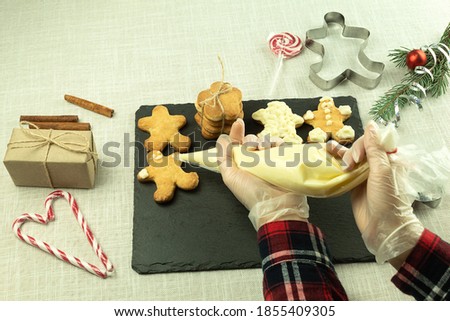 The girl applies cream to Christmas cookies. Decorating Christmas cookies with a pastry bag. Girl decorates cookies with interest