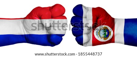 The concept of the struggle of peoples. Two hands are clenched into fists and are located opposite each other. Hands painted in the colors of the flags of the countries. France vs Costa Rica