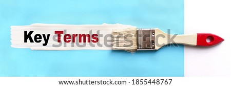 Business and finance concept. On a blue background, the surface is painted white with a brush, on which it is written Key Terms Royalty-Free Stock Photo #1855448767