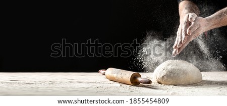 White flour flying into air as pastry chef in white suit slams ball dough on white powder covered table. concept of nature, Italy, food, diet and bio. Royalty-Free Stock Photo #1855454809
