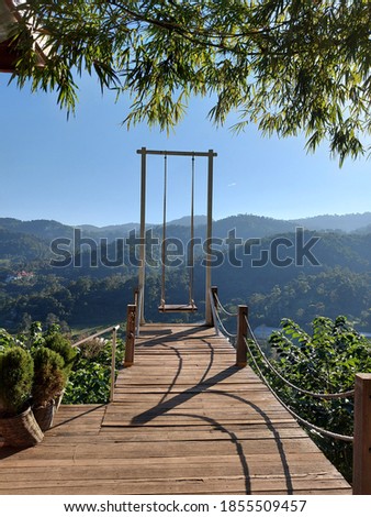 View photos with paths and swings behind beautiful mountains and sky.