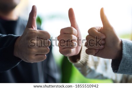 A group of people making thumb up hands sign 