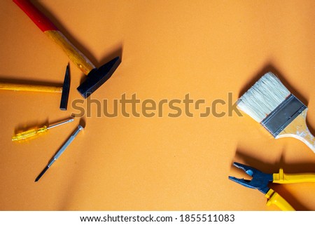 A top lay with a big brush, a pair of pliers, two hammers and two screwdrivers with copy space in the center