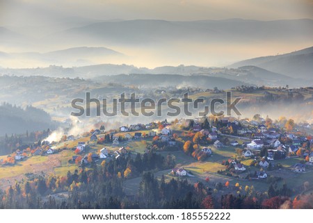 Vertical picture of the aerial view of mountain village with misty all in autumn colors