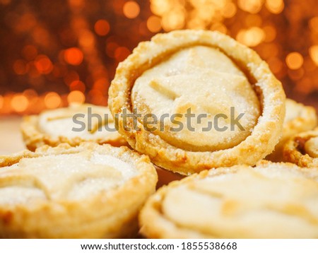 Fresh mince pies on a wooden board. Traditional Christmas pastry product. Warm glitter bokeh background