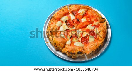 A Pepperoni pizza on a blue background isolated. Traditional Italian cuisine concept, pizza Margarita or Margherita over blue.