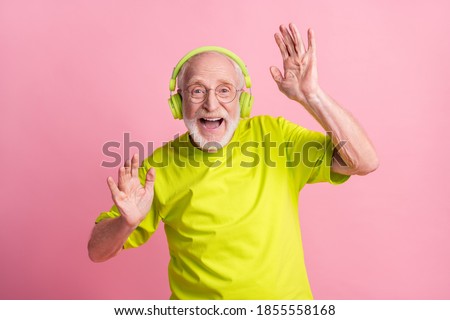 Photo of crazy optimistic old man listen music dance arms wear headphones spectacles lime color clothes isolated on pink background