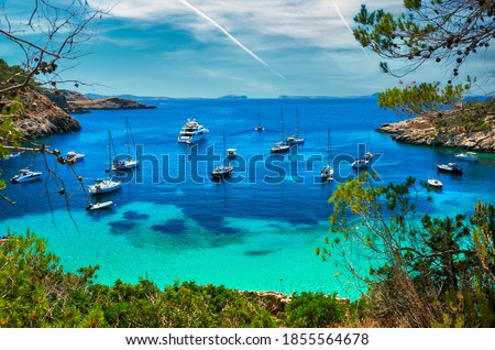 Moored vessels, sailboats, yachts, motorboats at Cala Salada turquoise lagoon cove. Idyllic beautiful place for vacationers and summer holidays, bright colour, Ibiza Island, Balearic Islands. Spain Royalty-Free Stock Photo #1855564678