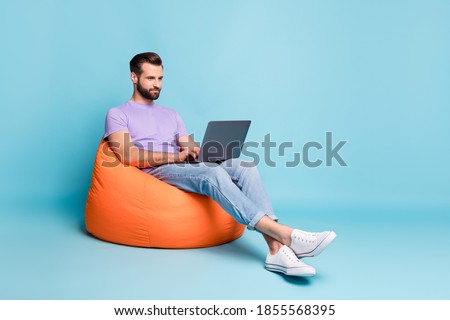 Full length body size photo of young entrepreneur working with laptop in beanbag isolated on bright blue color background empty space