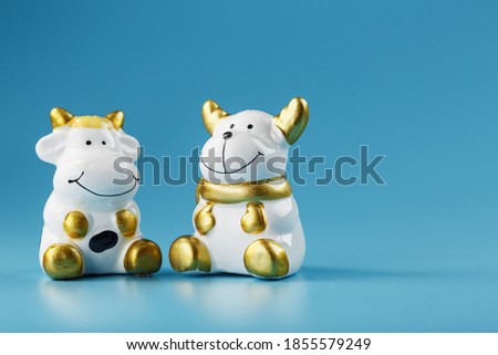 A pair of cow and bull figures on a blue background, with free space.