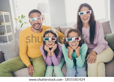 Photo of full big family four people sit couch watch film excited wear 3d specs colorful sweater pants in living room indoors