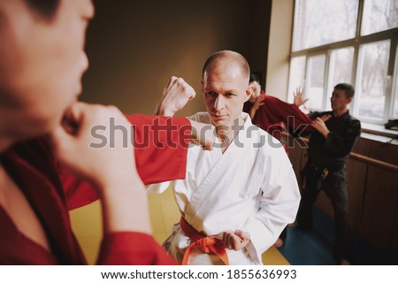 The bald man blocks while the opponent hits him. Couples of men in sparring practice techniques in the kart room. 