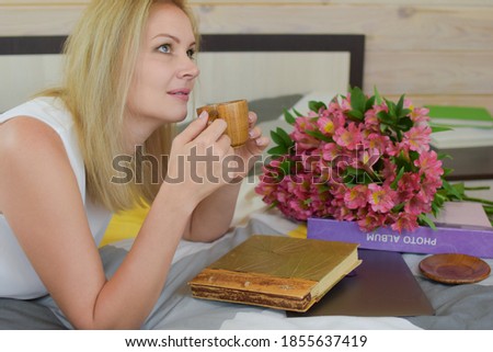 woman drinking a drink on the bed. morning coffee with fresh flowers. good mood