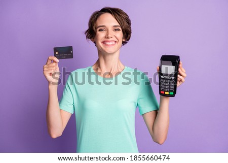 Photo of adorable young woman dressed casual turquoise clothes holding credit card atm terminal isolated violet color background