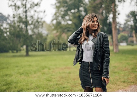 Portrait of girl, posing for picture, wearing black skirt, white sweater and black jacket.