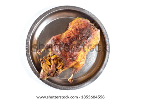 Duck stuffed with apples, baked in the oven lies on a steel tray, on a white background