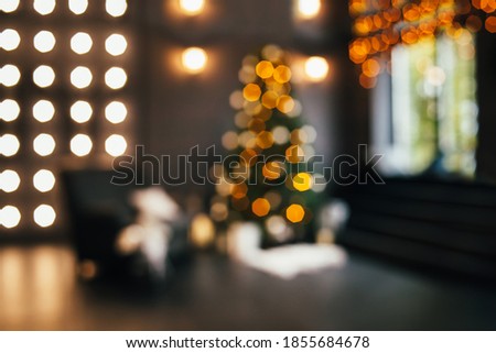 Blurred silhouette of a Christmas interior with lights glowing on the Christmas tree. Defocused Christmas tree with lights and ornaments. Abstract Christmas background.