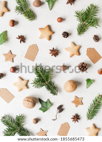 Natural christmas pattern from fir twigs and cones, cookies, nuts, wood stars, spices, and tags. Top view. Flat lay