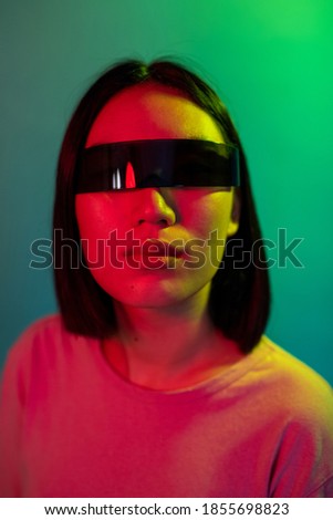 Young asian woman wearing smart glasses on colorful background enjoying augmented reality