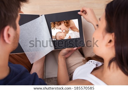 High angle view of young couple looking through photo album at home