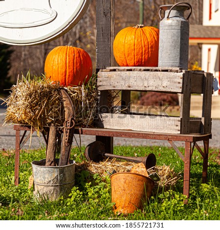 Yard decoration featuring straw bales, pumpkins, old household objects (rusty tools, metal pitchers and buckets) and a wooden case. Image for Halloween, thanksgiving, fall (autumn) concept