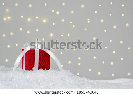 Christmas sale, buying gifts. Red gift on white snow. Background with bokeh