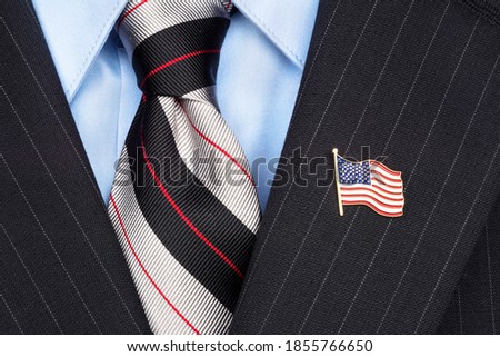 A symbolic American flag lapel pin on the collar of a businessman's suit Royalty-Free Stock Photo #1855766650