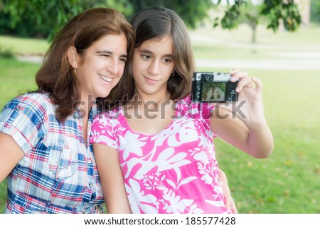 Hispanic teenager and her young mother taking a self picture at a beautiful park